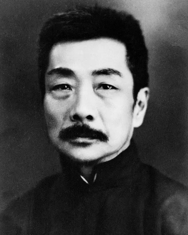 Lu Xun de frente, con bigote y túnica oscura, retrato de estudio de 1933